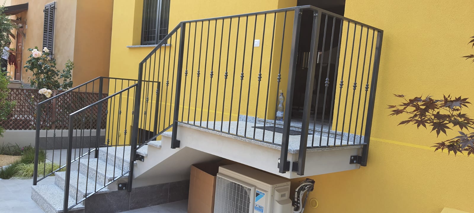 Scala esterna con ringhiera in ferro davanti a una facciata gialla realizzata da Gamma Metallica