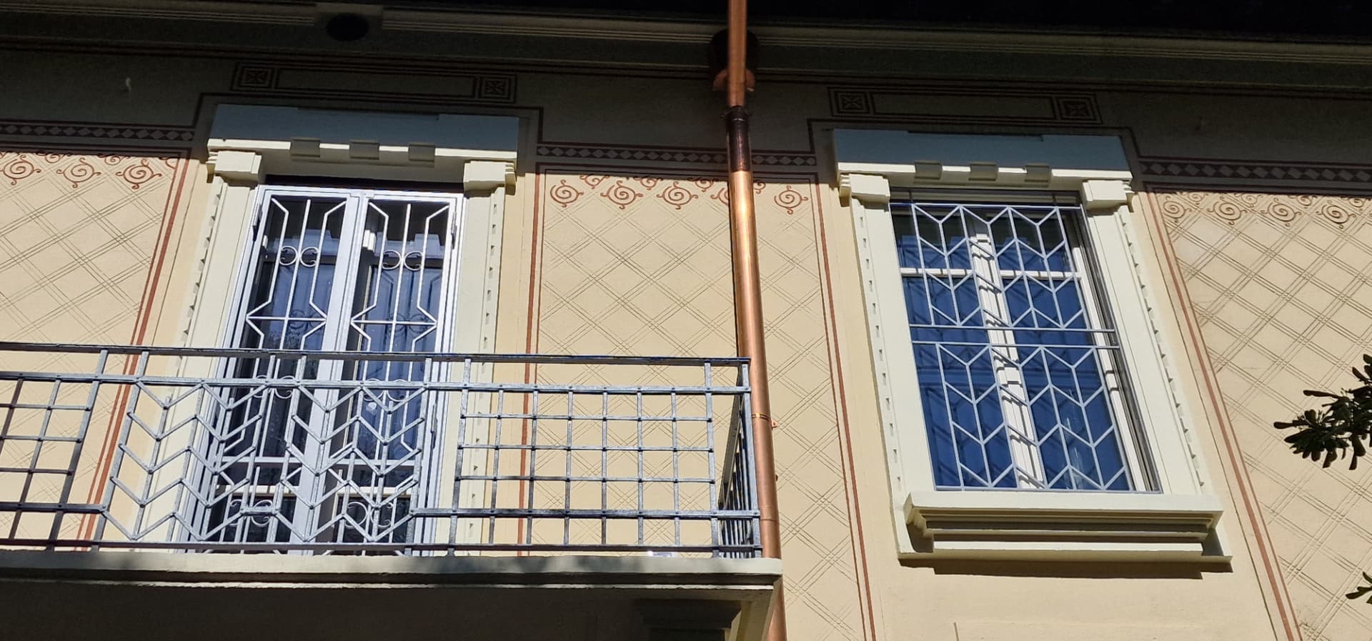Inferriate geometriche su portafinestra e finestra di una facciata decorata realizzate da Gamma Metallica