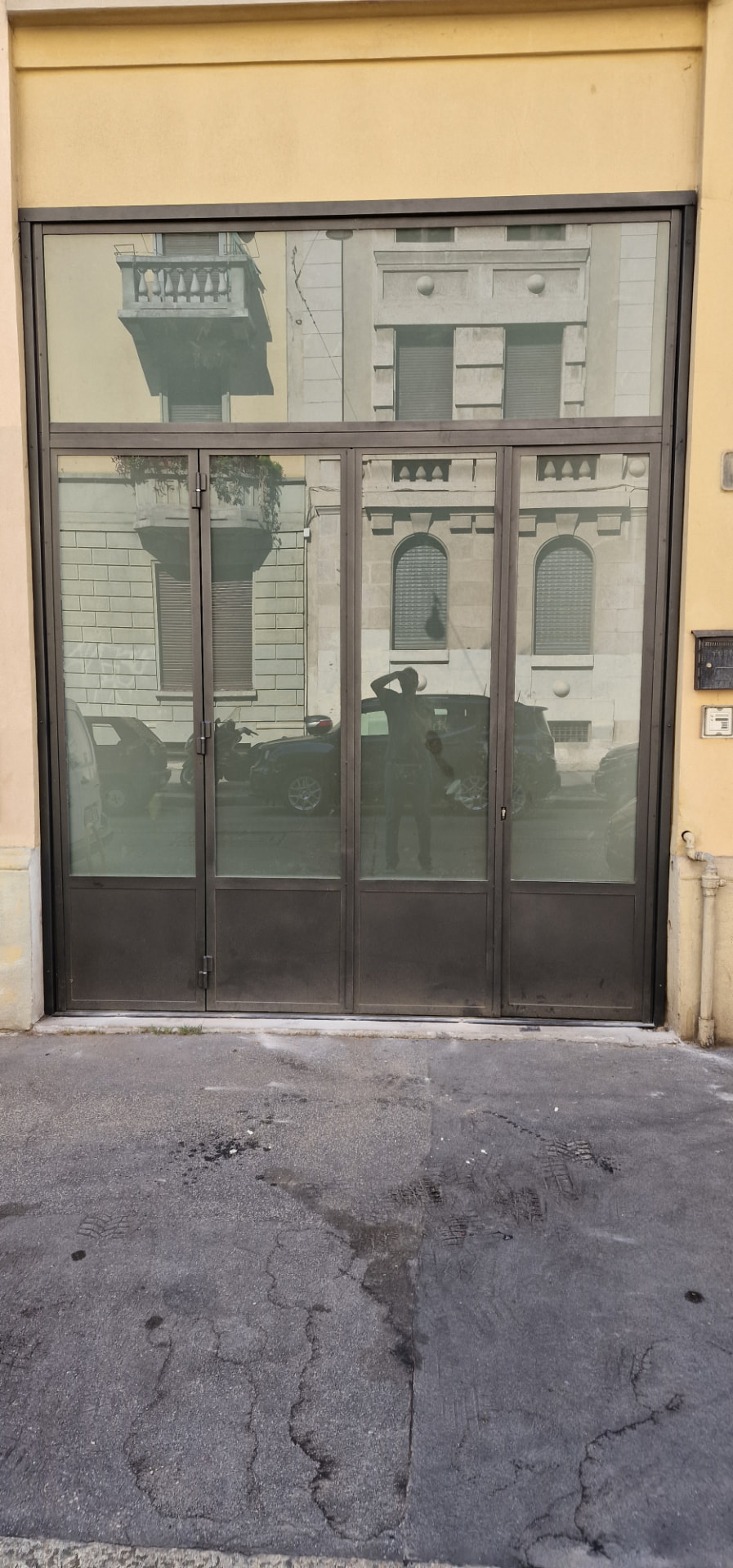 Porta in ferro e vetro con trasom superiore su una facciata giallo chiaro realizzata da Gamma Metallica